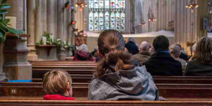 A Mum and child sat on pews during a service