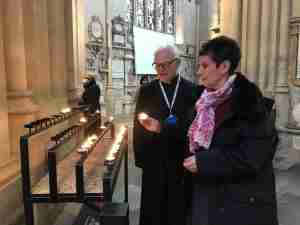Visitor lighting a candle with a Bath Abbey chaplain