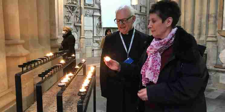 Visitor lighting a candle with a Bath Abbey chaplain