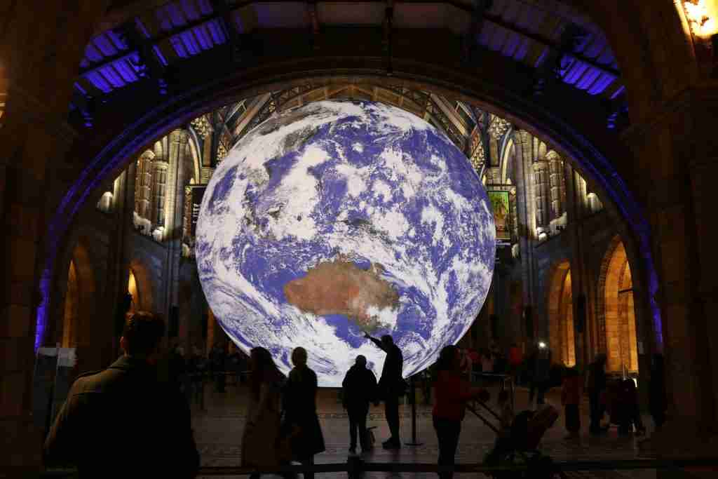 Large scale model of the Earth with people stood in front