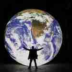 Man silhouetted in front of large lit up globe