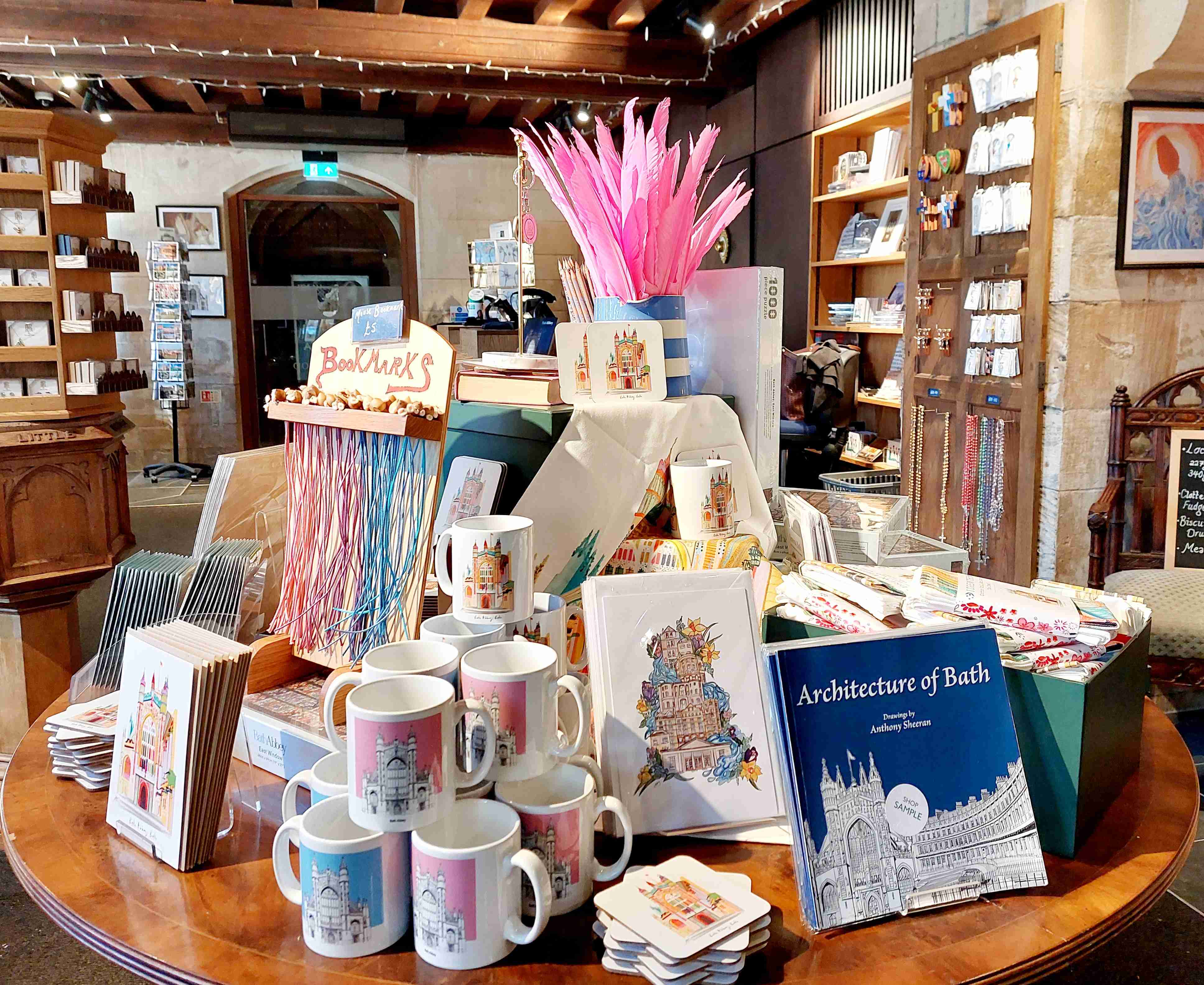 Shop table display featuring colourful mugs, feather pens and architecture book