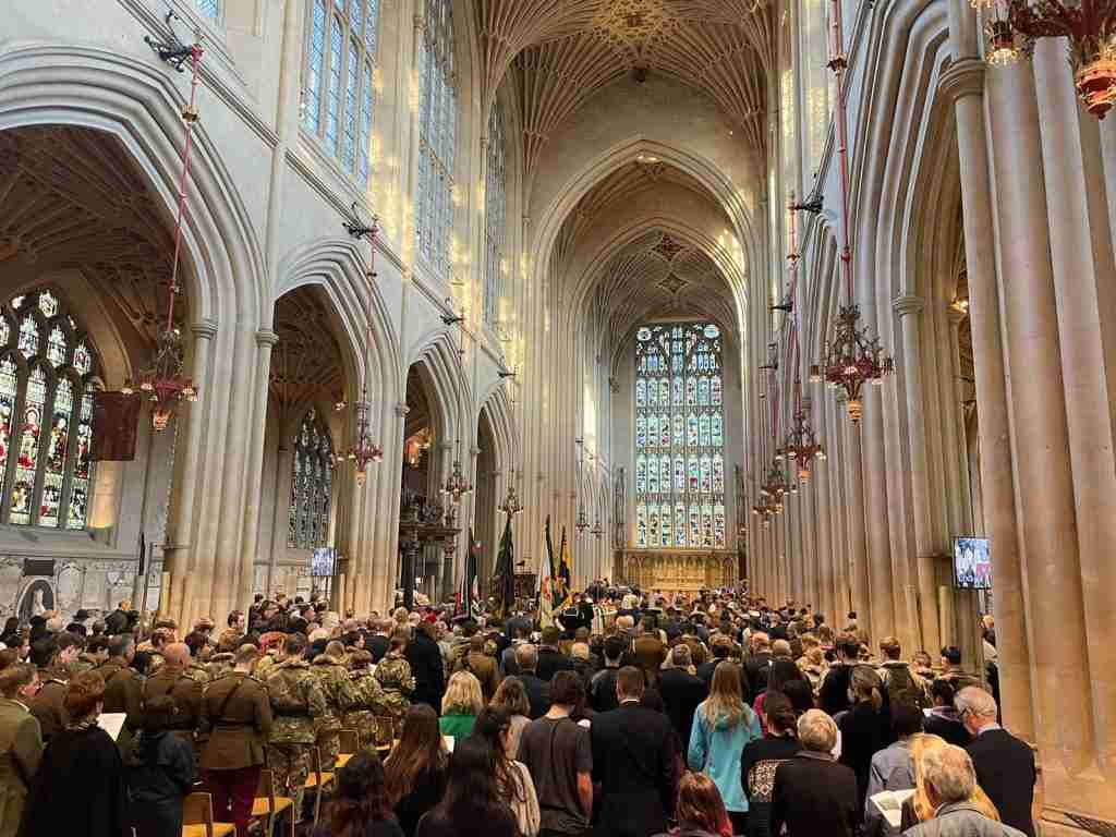 People and soldiers stand in Bath Abbey to listen to a service