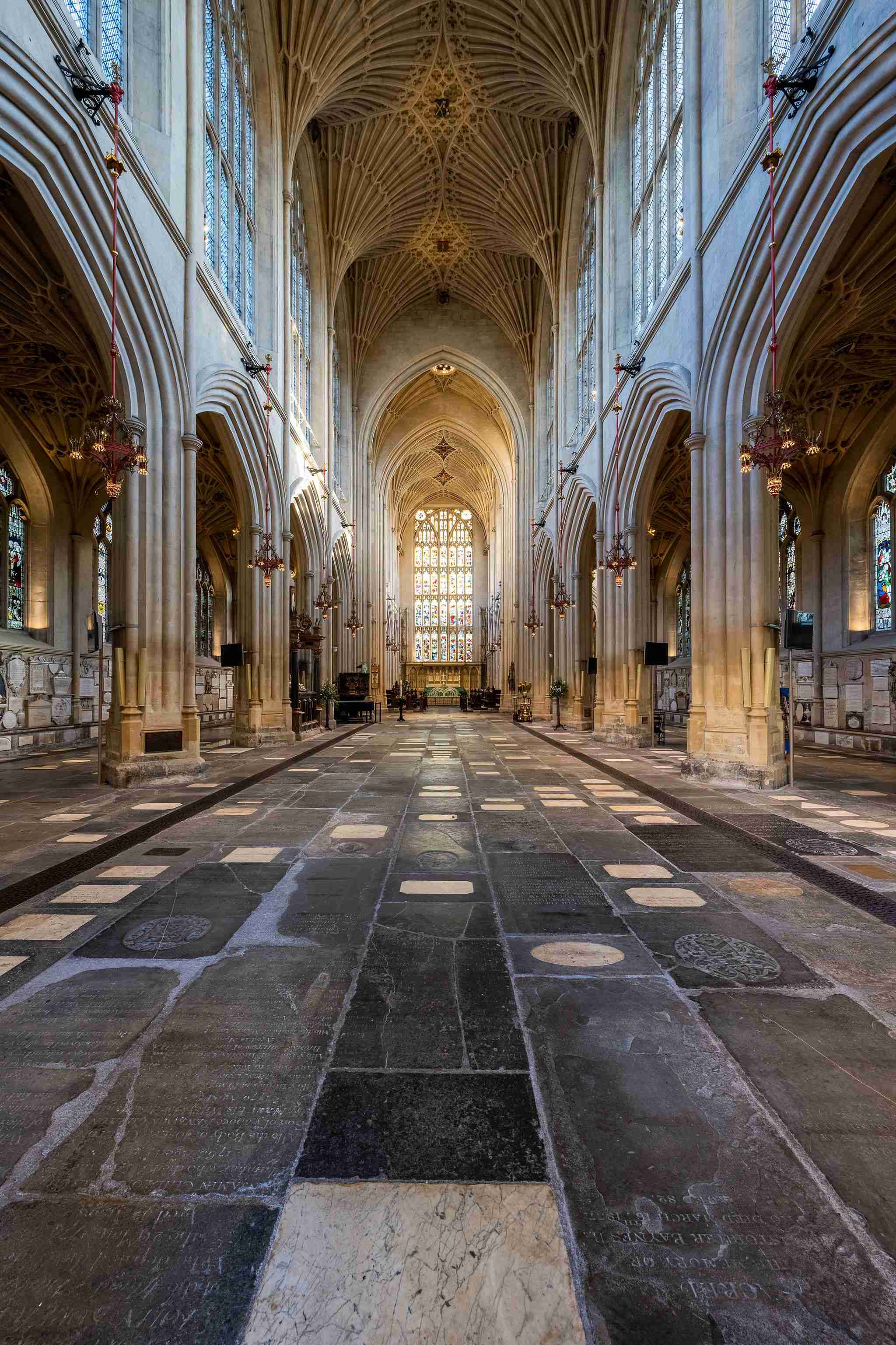 Memorial ledgerstones on Bath Abbey's floor, looking down the nave towards the altar and east window