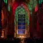 Bath Abbey interior lit up in red and green during the Advent Carol Service.