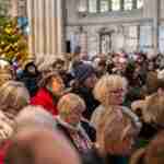 People sat in Bath Abbey listening to a service with a Christmas tree is the background