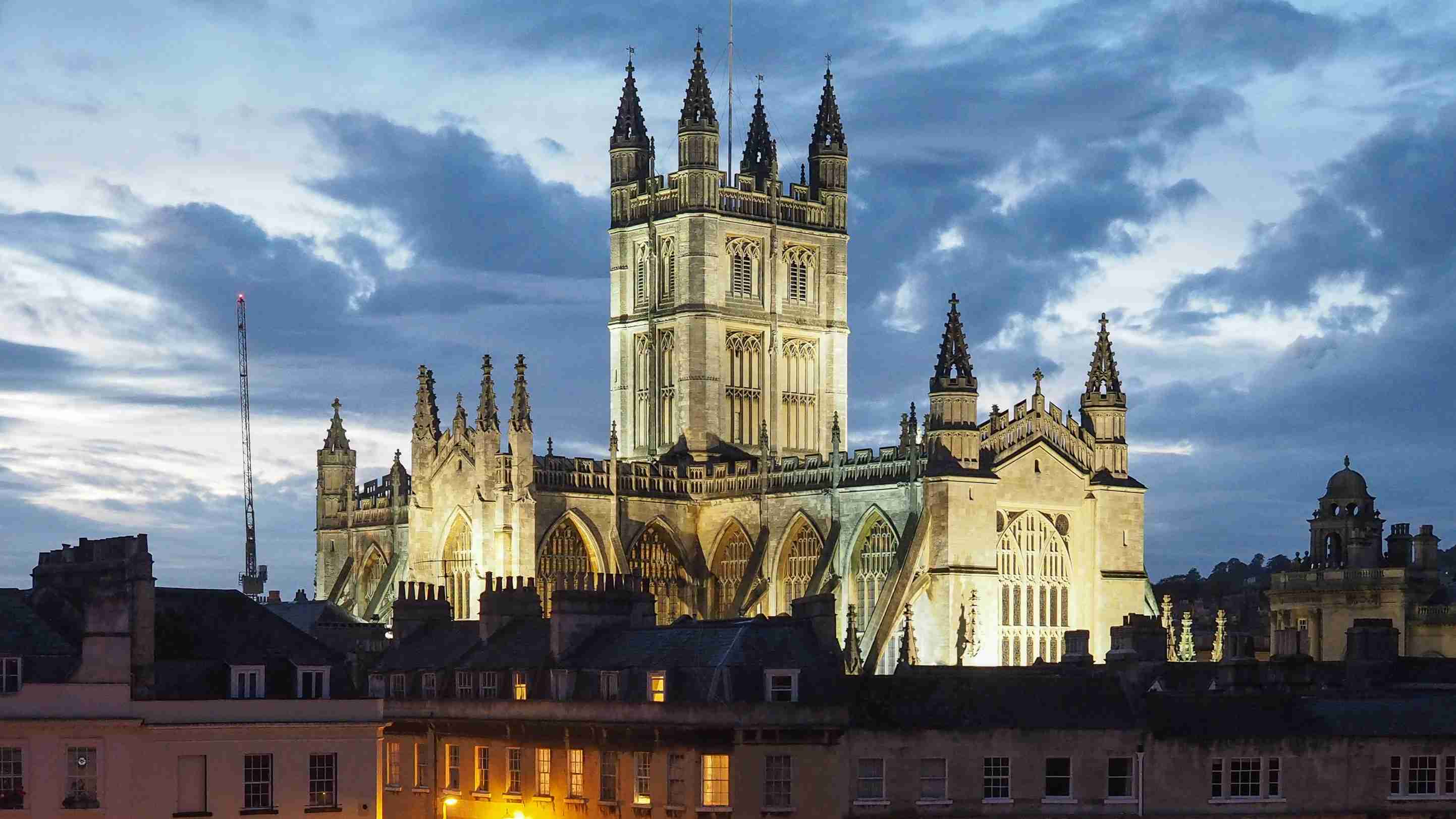 Bath Abbey in twilight across the roofs of houses